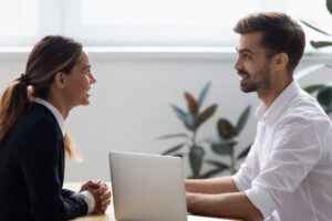 Image of a HR professional speaking with an employee in front of a laptop